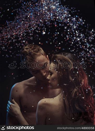 Young attractive lovers cuddling in crystal rain