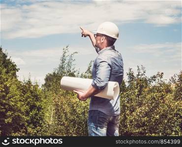 Young, attractive man holding paper project in the park against the backdrop of green trees. Close-up. Concept of labor and employment. Man holding paper project in the park