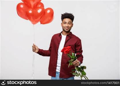 Young attractive man holding red balloon and rose for surprising his girlfriend. Young attractive man holding red balloon and rose for surprising his girlfriend.