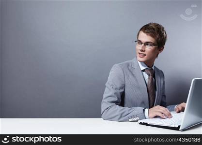Young attractive man in a suit with the laptop looks back