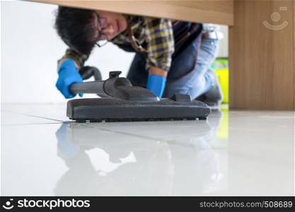 Young attractive man is cleaning vacuum commercial cleaning equipment on floor at home helping wife