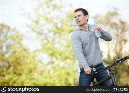 Young attractive man on a bicycle drink water