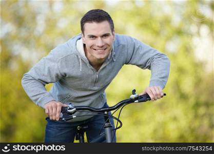 Young attractive man riding his bicycle in the park