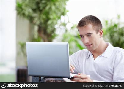 Young attractive man with a laptop in a cafe