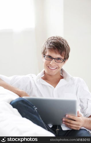 Young attractive man with laptop on sofa