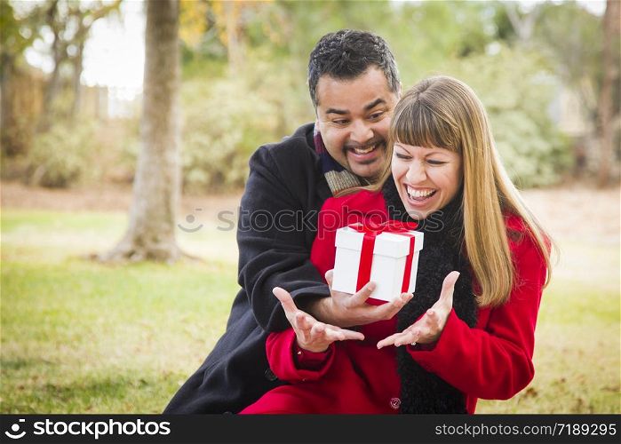 Young Attractive Mixed Race Couple Sharing Christmas or Valentines Day Gift in the Park.
