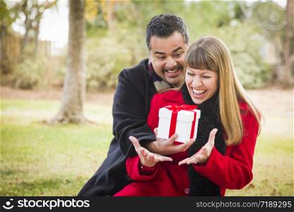 Young Attractive Mixed Race Couple Sharing Christmas or Valentines Day Gift in the Park.