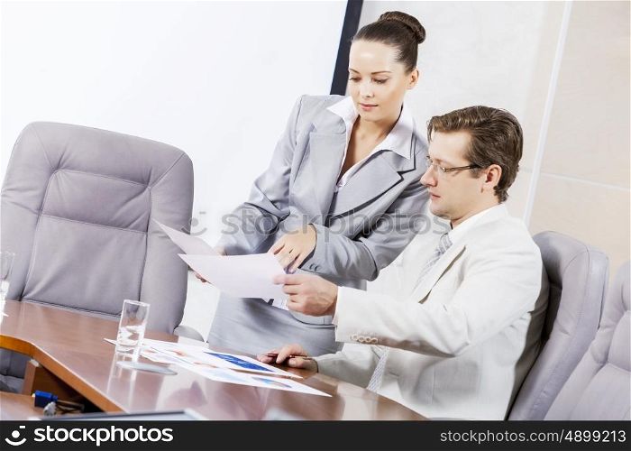 Young attractive secretary showing boss business documents. Office work moments