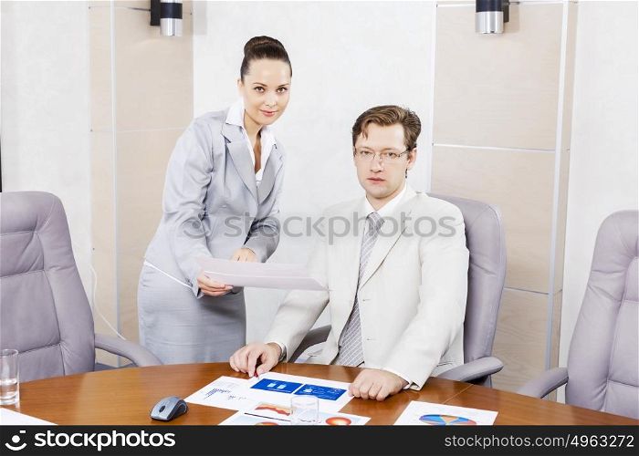 Young attractive secretary showing boss business documents. Office work moments