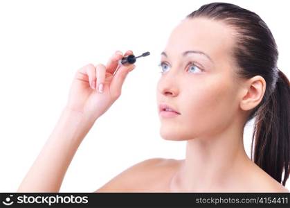 young attractive sensual woman is applying cosmetics on her face and looking sideways, isolated on white