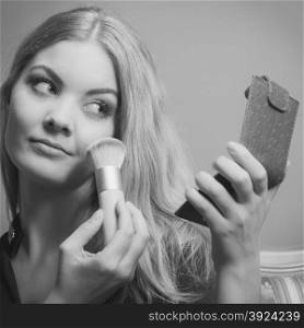 Young attractive woman applying make up with powder brush. Pretty gorgeous girl beautifying. Fashion and makeup. Black &amp;amp; white photo.