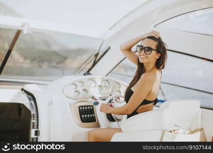 Young attractive woman drives a  yacht at sea at sunny day