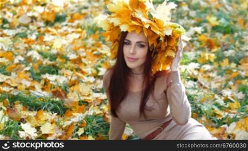 Young attractive woman enjoying autumn day in the park, looking at camera