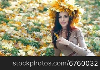 Young attractive woman enjoying autumn day in the park, looking at camera
