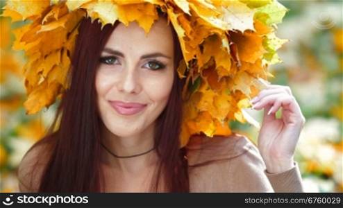 Young attractive woman enjoying autumn day in the park, looking at camera, closeup