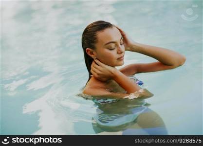 Young attractive woman enjoys in the outdoor pool in summer time