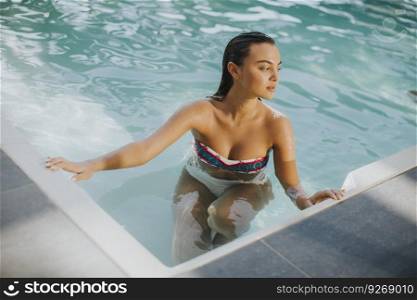 Young attractive woman enjoys in the outdoor pool in summer time