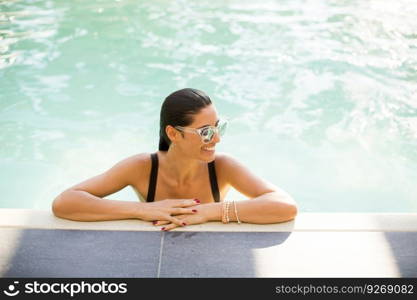 Young attractive woman enjoys in the outdoor pool in summer time