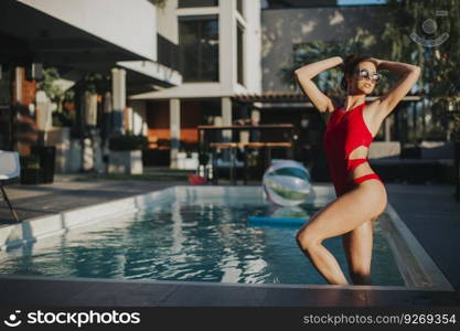 Young attractive woman enjoys in the outdoor pool in summer time