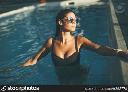 Young attractive woman enjoys in the outdoor swimming pool in summer time