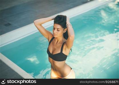 Young attractive woman enjoys in the outdoor swimming pool in summer time