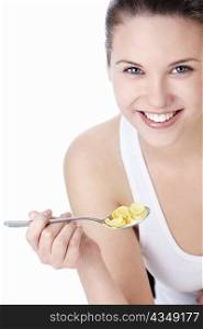 Young attractive woman holding a spoonful of corn flakes on a white background