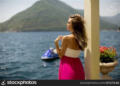 Young attractive woman in a dress relaxing by the sea at sunny day