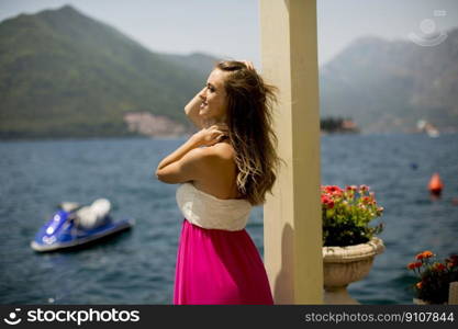 Young attractive woman in a dress relaxing by the sea at sunny day