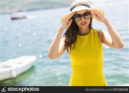 Young attractive woman in a yellow dress relaxing by the sea at sunny day