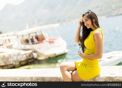 Young attractive woman in a yellow dress relaxing by the sea at sunny day