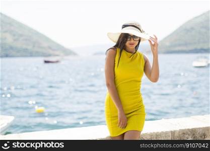Young attractive woman in a yellow dress relaxing by the sea at sunny day
