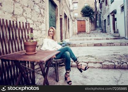 Young attractive woman in fashionable white blouse and blue jeans poses.City lifestyle.Female fashion concept.Retro and vintage filter and colors effect used.. woman in fashionable white blouse and blue jeans poses