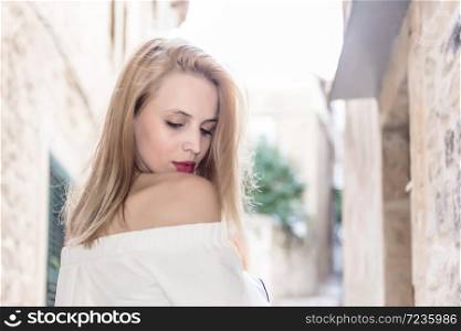 Young attractive woman in fashionable white blouse poses.City lifestyle.Female fashion concept.Retro and vintage filter and colors effect used.. attractive woman in fashionable white blouse poses
