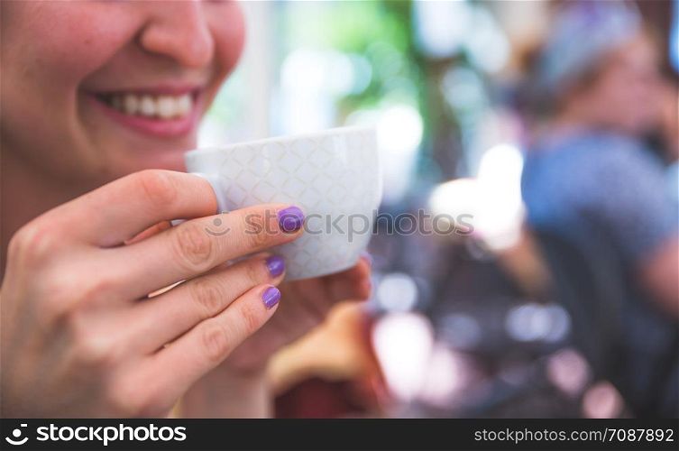 Young attractive woman is drinking a cup of coffee in an Italian cafe