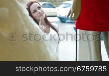 Young attractive woman looking excitedly into the window of a shop