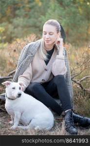 Young attractive woman playing with dog outdoors in the autumn park