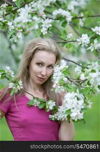 young attractive woman standing near the blossoming apple tree.