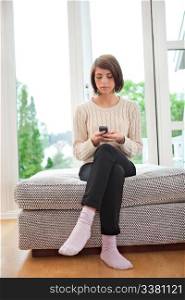 Young attractive woman text messaging while sitting on couch