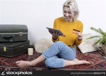young attractive woman using her credit card to make an online purchase with a digital touchscreen tablet at home.