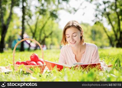 Young attravctive woman in summer park having picnic. Sunny weekend in park