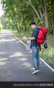Young backpacker man traveler with map,  He carry large backpack during relaxing outdoor on summer vacations in forest trial, copy space