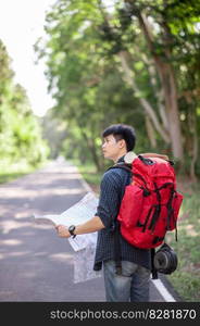 Young backpacker man traveler with map,  He carry large backpack during relaxing outdoor on summer vacations in forest trial, copy space