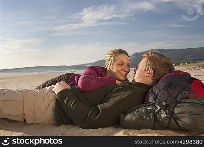 Young backpackers lying on beach