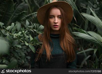 Young baeutiful woman standing at nursery in a greenhouse.. Woman standing at nursery in a greenhouse