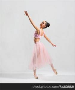 Young ballerina on grey background