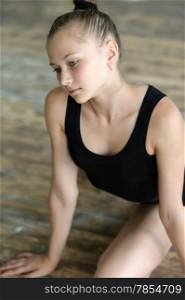 Young ballet dancer stretching her legs on the floor