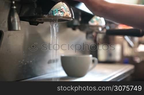 Young barista brewing esspresso using proffessional tools for coffe preparation in a cafe