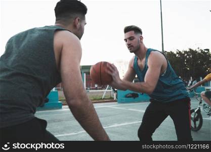 Young basketball players playing one-on-one on outdoor court. Sport and basketball concept.