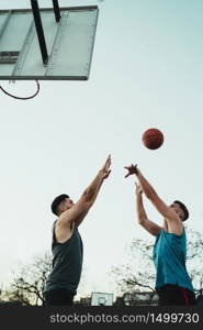 Young basketball players playing one-on-one on outdoor court. Sport and basketball concept.