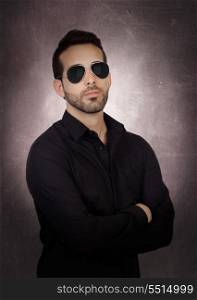Young bearded businessman with sunglasses on a over gray and irregular background